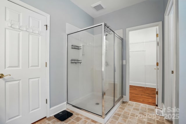 full bath with a stall shower, baseboards, and a spacious closet
