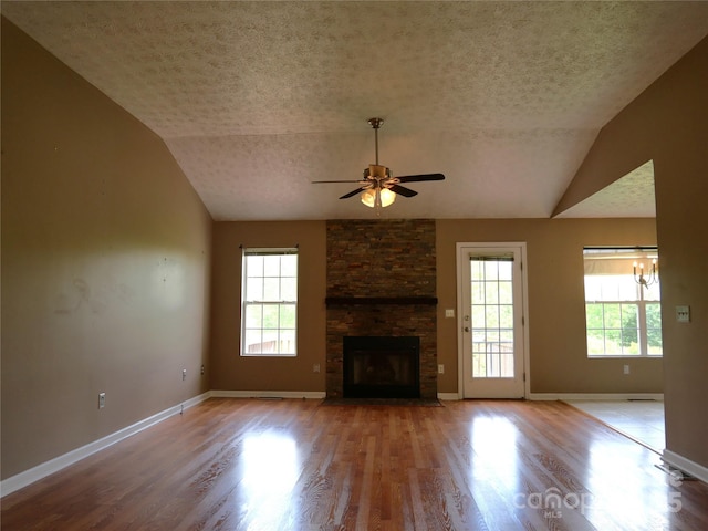 37 S Woodridge View Ct, Hendersonville, NC 28791 - unfurnished living room featuring a textured ceiling, ceiling fan, a stone fireplace, lofted ceiling, and plenty of natural light