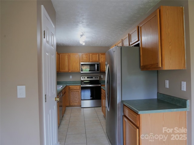 37 S Woodridge View Ct, Hendersonville, NC 28791 - kitchen with appliances with stainless steel finishes, light tile patterned floors, brown cabinetry, a textured ceiling, and dark countertops