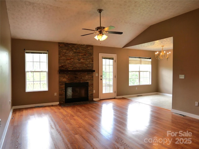 37 S Woodridge View Ct, Hendersonville, NC 28791 - unfurnished living room featuring wood finished floors, a chandelier, a stone fireplace, ceiling fan, and a textured ceiling