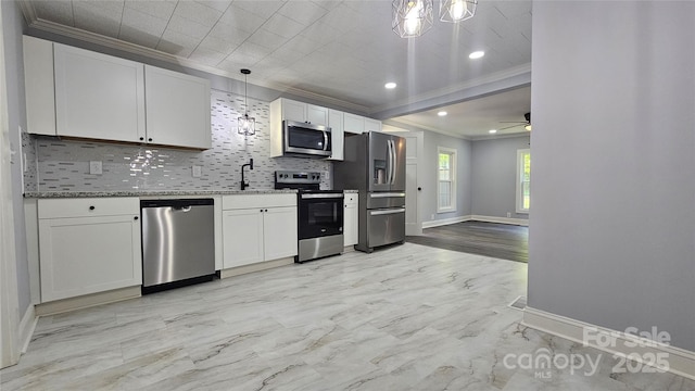 kitchen with appliances with stainless steel finishes, ornamental molding, backsplash, white cabinetry, and baseboards