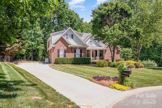 view of front of property with brick siding, a front lawn, and concrete driveway