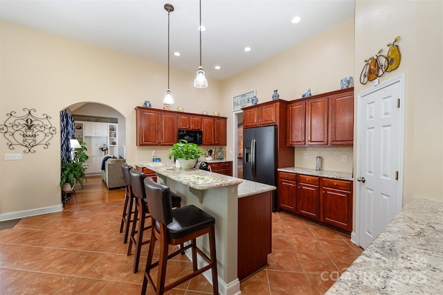 kitchen with black appliances, tile patterned floors, arched walkways, backsplash, and a high ceiling