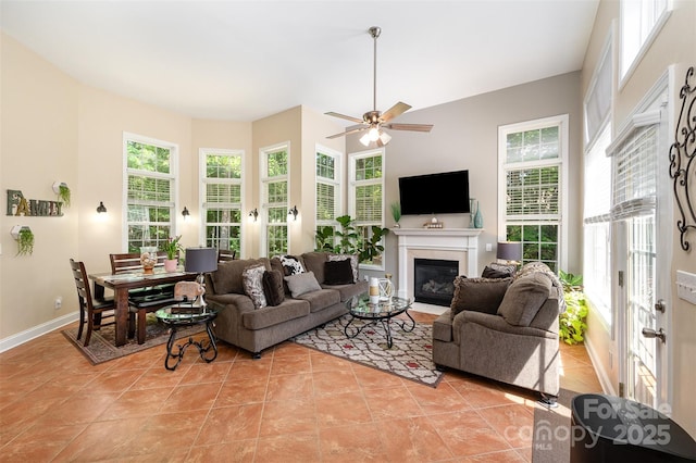 living area featuring healthy amount of natural light, a fireplace with flush hearth, light tile patterned floors, and ceiling fan
