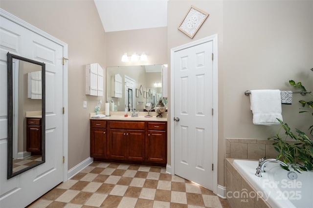 bathroom with a bath, vanity, baseboards, vaulted ceiling, and tile patterned floors