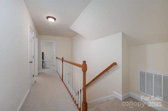 hallway with an upstairs landing, light carpet, and baseboards