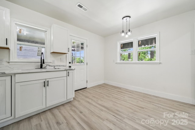 1417 W Monroe St, Salisbury, NC 28144 - kitchen featuring a sink, light wood finished floors, white cabinetry, baseboards, and decorative light fixtures