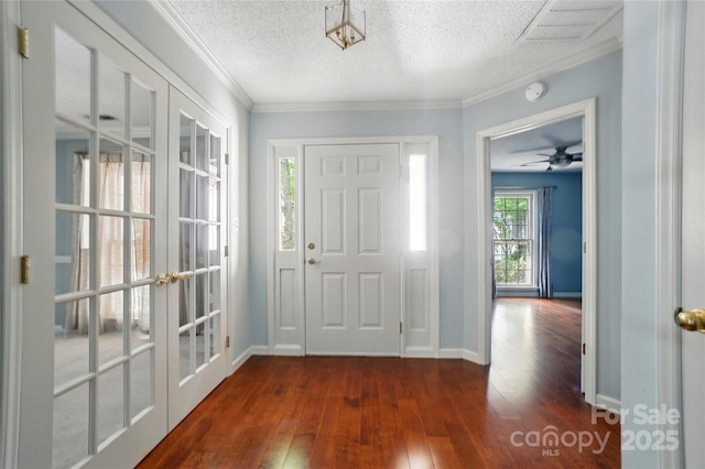 entrance foyer with french doors, dark wood-style flooring, a textured ceiling, baseboards, and ornamental molding
