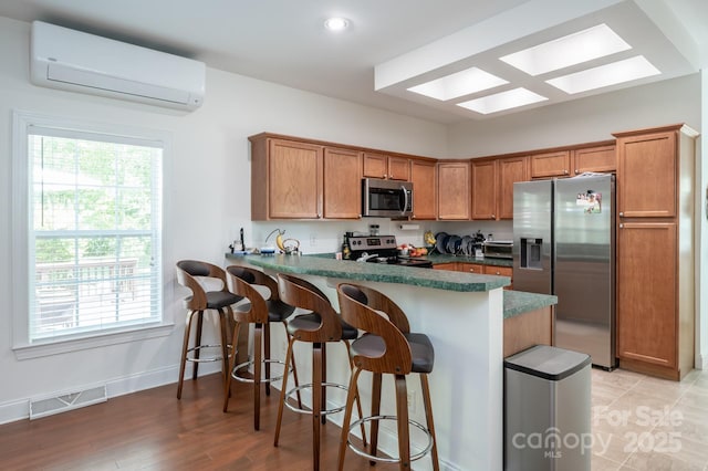 19 Lynnbrook Way, Columbus, NC 28722 - kitchen featuring stainless steel appliances, a wall unit AC, a peninsula, brown cabinets, and recessed lighting