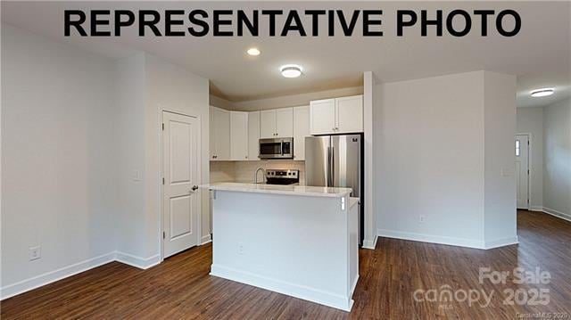 kitchen with stainless steel appliances, white cabinetry, dark wood finished floors, and light countertops