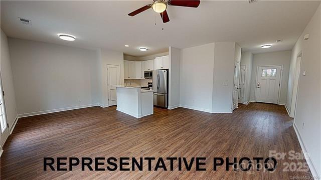 kitchen featuring appliances with stainless steel finishes, open floor plan, a ceiling fan, dark wood finished floors, and light countertops