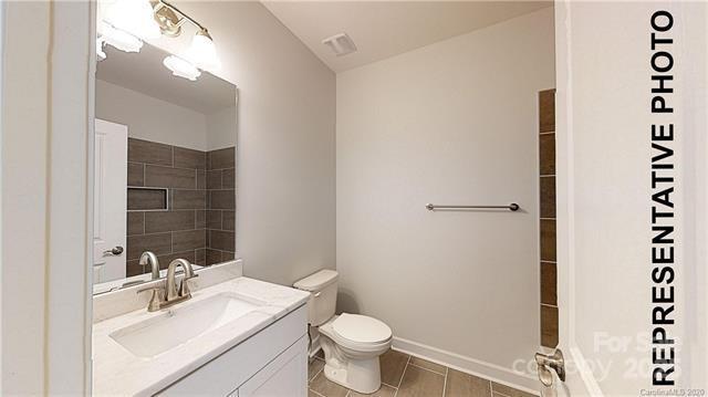 bathroom featuring toilet, vanity, tile patterned flooring, and baseboards