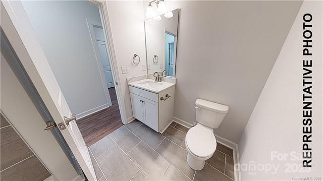 bathroom with toilet, vanity, tile patterned floors, and baseboards