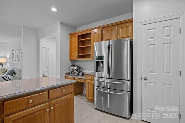 15831 Breton Brook St, Huntersville, NC 28078 - kitchen with stainless steel fridge, open shelves, light tile patterned floors, light stone counters, and brown cabinets