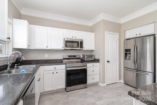 kitchen with appliances with stainless steel finishes, a sink, white cabinets, crown molding, and baseboards