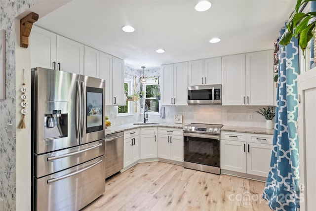 27037 Tidal Way, Tega Cay, SC 29708 - kitchen featuring appliances with stainless steel finishes, a sink, light wood-style flooring, white cabinetry, and light stone countertops