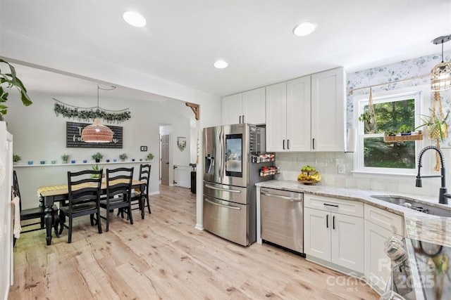 27037 Tidal Way, Tega Cay, SC 29708 - kitchen featuring appliances with stainless steel finishes, a sink, light stone countertops, light wood-style floors, and white cabinets