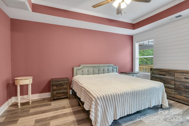 bedroom with wood finished floors, crown molding, baseboards, and ceiling fan