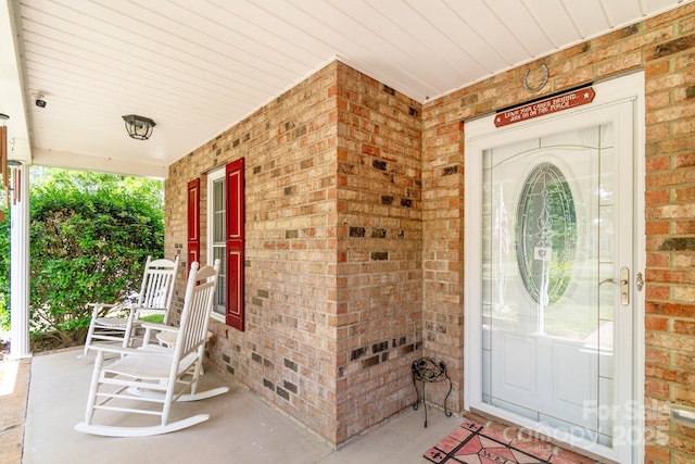 property entrance featuring brick siding and covered porch