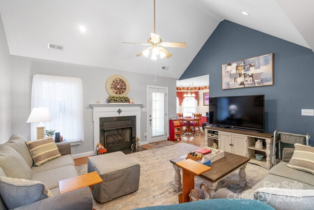 living room with ceiling fan, a fireplace with flush hearth, wood finished floors, high vaulted ceiling, and baseboards