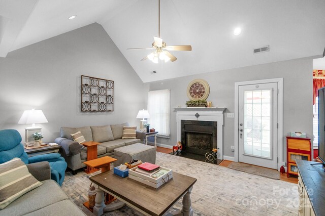 living room with ceiling fan, a fireplace with flush hearth, high vaulted ceiling, wood finished floors, and baseboards