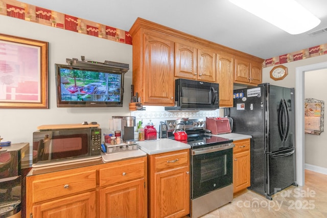kitchen with black appliances, backsplash, light countertops, and brown cabinetry