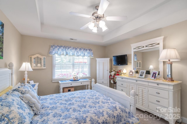 bedroom with a tray ceiling, dark carpet, and a ceiling fan