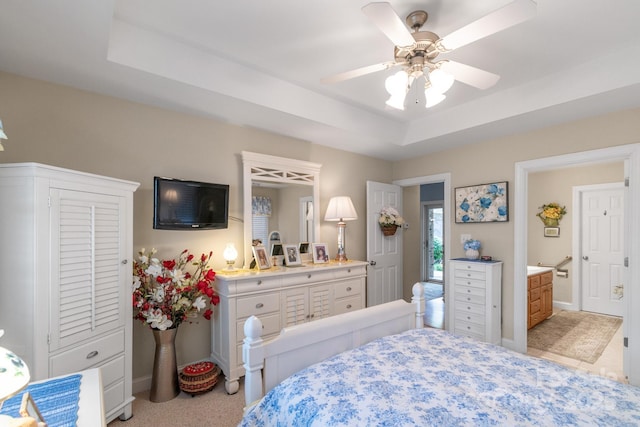 bedroom featuring a tray ceiling, light carpet, baseboards, and ensuite bathroom