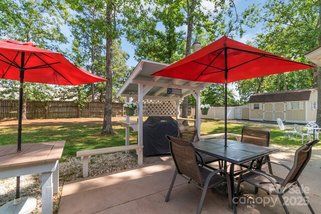 view of patio / terrace featuring outdoor dining area, a storage unit, an outdoor structure, and grilling area