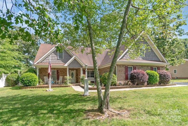 view of front facade featuring brick siding, a front yard, and a porch