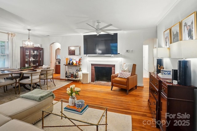 4647 General Pershing Dr, Charlotte, NC 28209 - living room with arched walkways, a ceiling fan, a brick fireplace, wood finished floors, and crown molding