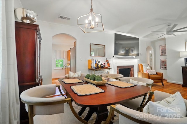 4647 General Pershing Dr, Charlotte, NC 28209 - dining area featuring arched walkways, a fireplace, wood finished floors, and a ceiling fan