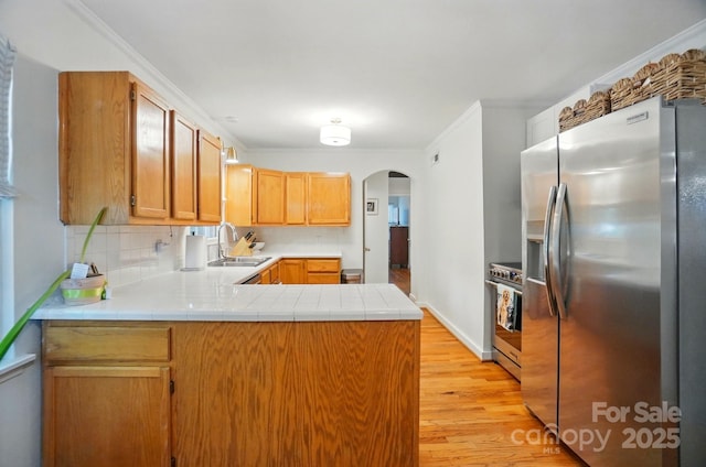 4647 General Pershing Dr, Charlotte, NC 28209 - kitchen featuring appliances with stainless steel finishes, a sink, arched walkways, light wood-style flooring, and a peninsula