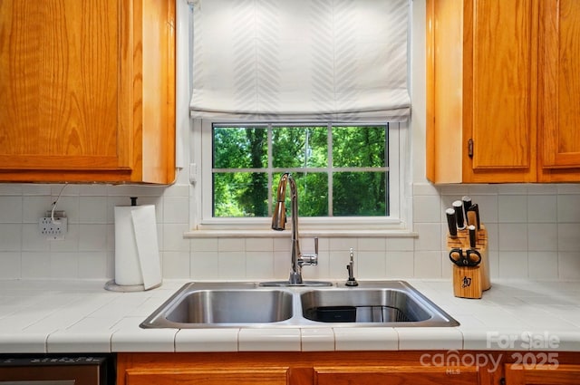 4647 General Pershing Dr, Charlotte, NC 28209 - kitchen with a sink, tasteful backsplash, brown cabinetry, and tile counters