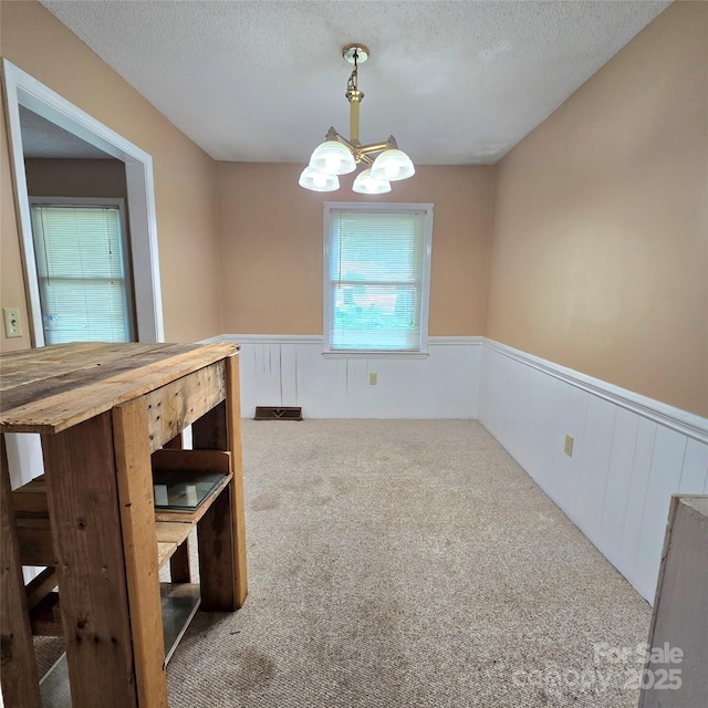 6573 Weldon Cir NW Unit 22, Concord, NC 28027 - unfurnished dining area featuring wainscoting, a chandelier, carpet floors, and a textured ceiling