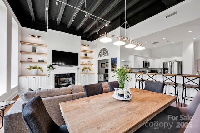 dining area with a towering ceiling, wood finished floors, a fireplace, and recessed lighting