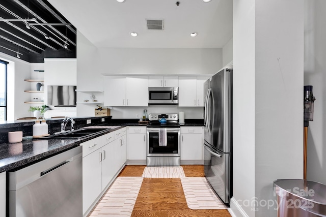 kitchen with appliances with stainless steel finishes, a sink, white cabinetry, open shelves, and light wood finished floors