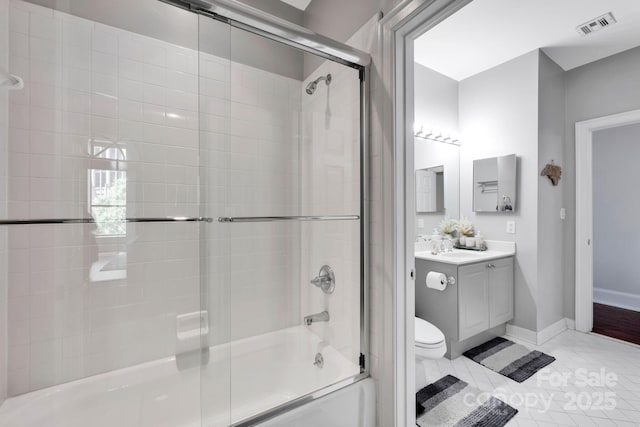 bathroom with vanity, shower / bath combination with glass door, toilet, tile patterned flooring, and baseboards