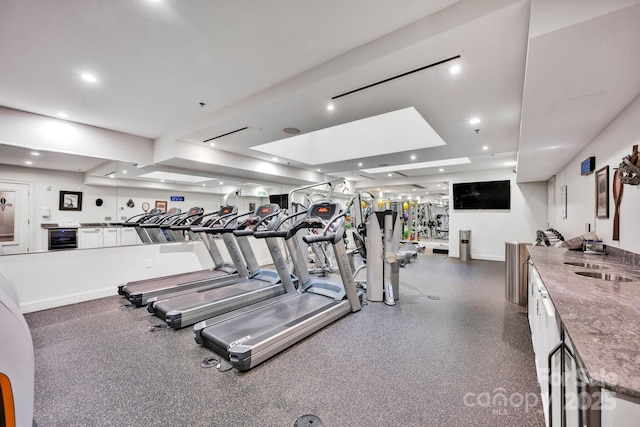 exercise room with a sink, baseboards, and beverage cooler