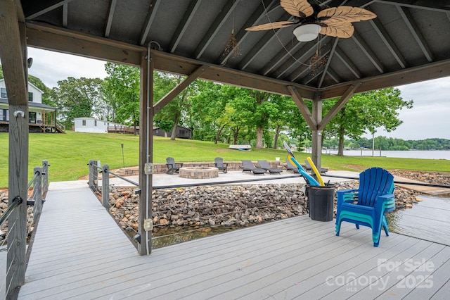 dock with an outdoor fire pit, a yard, and a deck with water view
