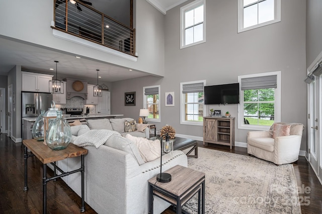 living room with a towering ceiling, baseboards, dark wood-type flooring, and a chandelier