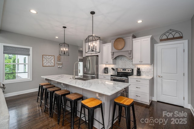 kitchen featuring appliances with stainless steel finishes, a sink, backsplash, a breakfast bar area, and baseboards