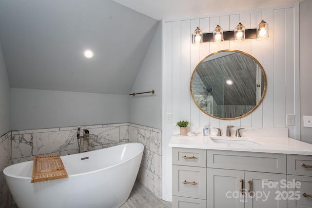 full bathroom featuring tile walls, vanity, a freestanding bath, vaulted ceiling, and a tile shower
