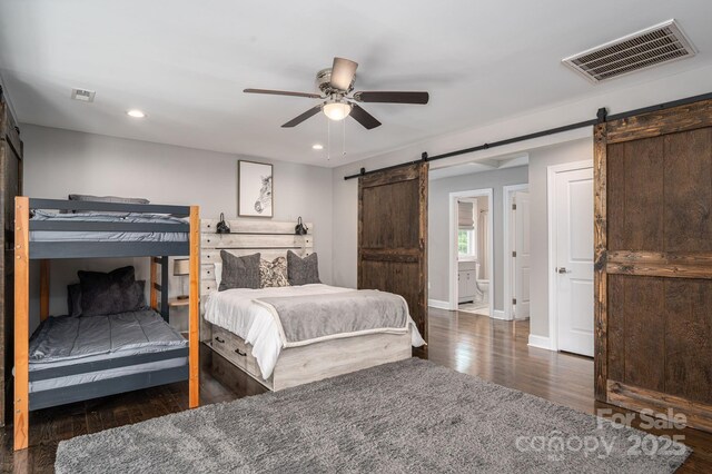 bedroom featuring a barn door, wood finished floors, recessed lighting, baseboards, and a ceiling fan