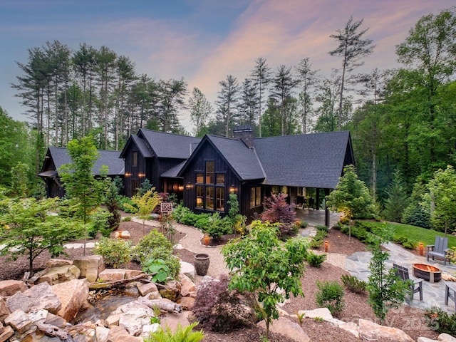 276 Stone Field Trl, Brevard, NC 28712 - view of front of property featuring a fire pit, a shingled roof, a chimney, a patio area, and board and batten siding