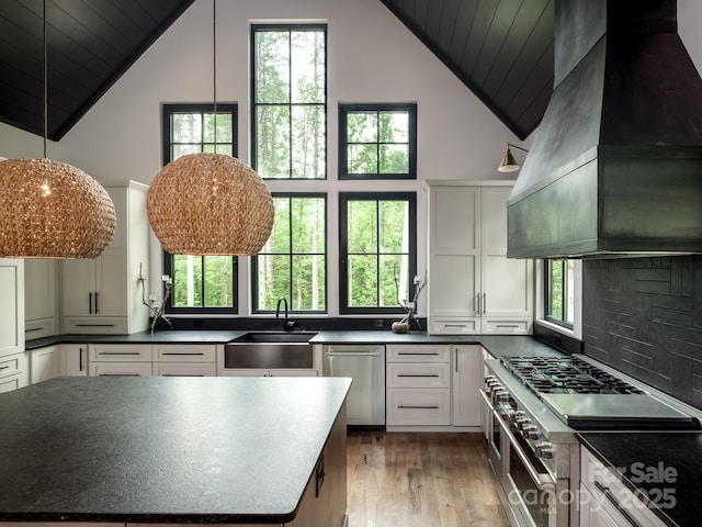 276 Stone Field Trl, Brevard, NC 28712 - kitchen featuring wall chimney range hood, stainless steel appliances, dark countertops, a sink, and light wood-style floors