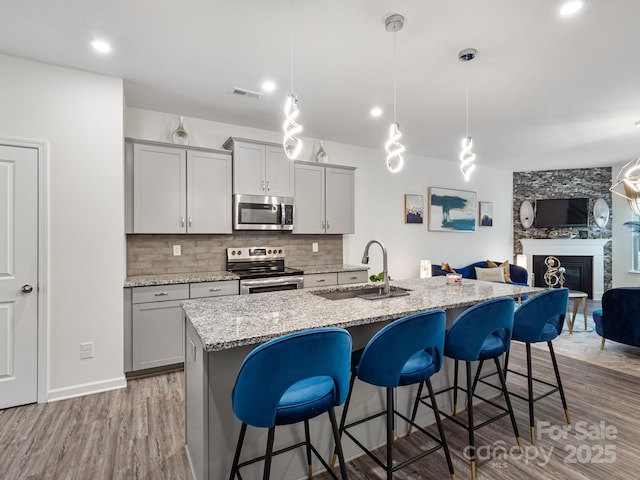 6381 Trinity Crossing Cir, Kannapolis, NC 28081 - kitchen with stainless steel appliances, a sink, gray cabinetry, a breakfast bar, and open floor plan