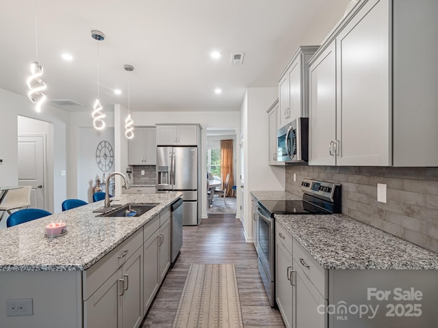 6381 Trinity Crossing Cir, Kannapolis, NC 28081 - kitchen with stainless steel appliances, a sink, wood finished floors, backsplash, and an island with sink