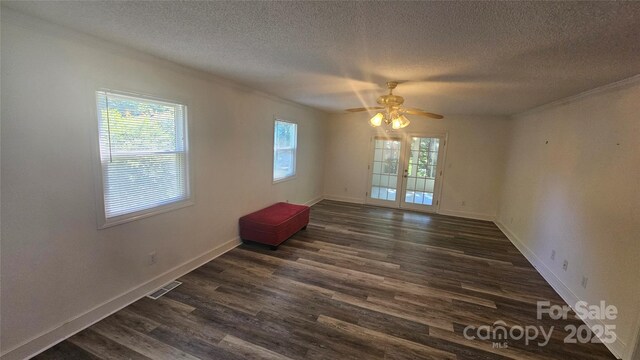 spare room with crown molding, a textured ceiling, dark wood finished floors, baseboards, and a ceiling fan