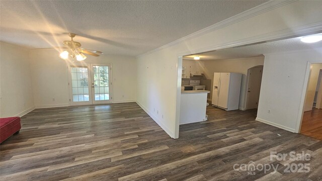 unfurnished living room featuring a ceiling fan, arched walkways, dark wood-style floors, a textured ceiling, and ornamental molding